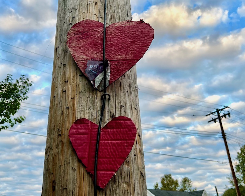 two heart shapes cut from cardboard attached to utility pole